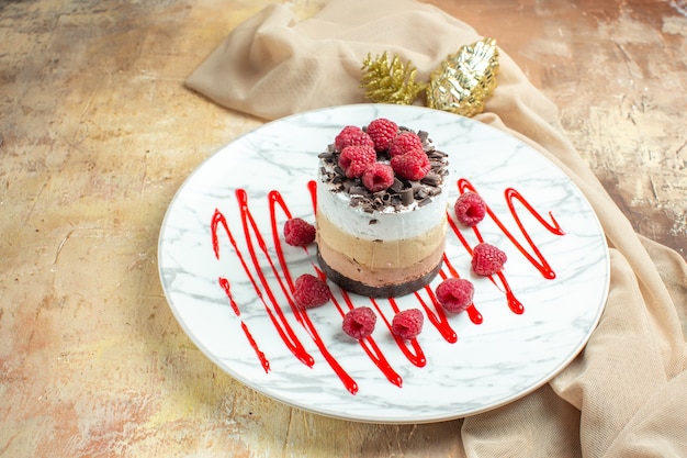 Front view delicious creamy cake inside plate with fresh raspberries on brown table