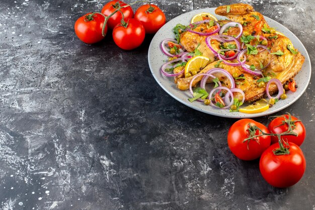 Вид спереди вкусного ужина из жареной курицы с различными специями и помидорами со стеблями слева на темном фоне