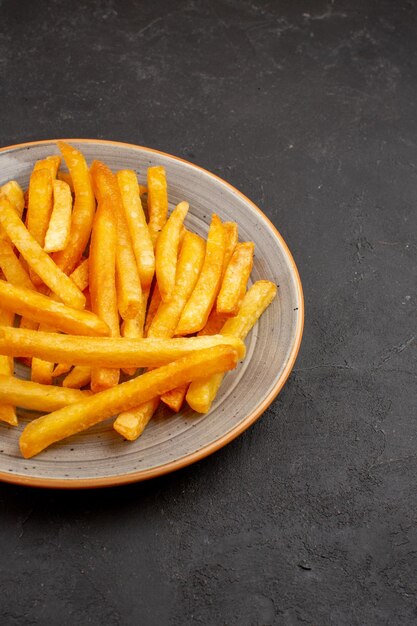 Front view delicious french fries inside plate on dark space