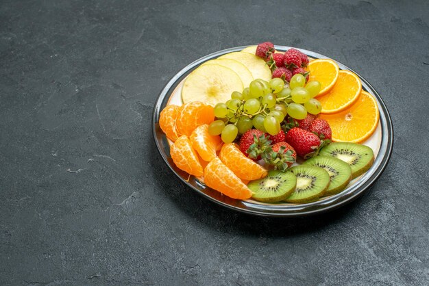 Вид спереди вкусная фруктовая композиция, свежие нарезанные и спелые фрукты на темном фоне, спелые свежие спелые фрукты для здоровья
