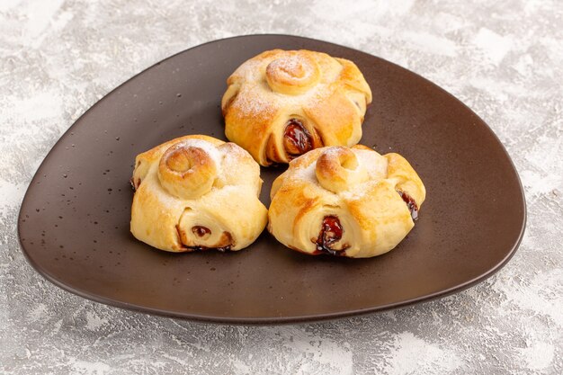 Front view delicious fruity cake sweet baked inside brown plate on the grey table cake pastry sweet