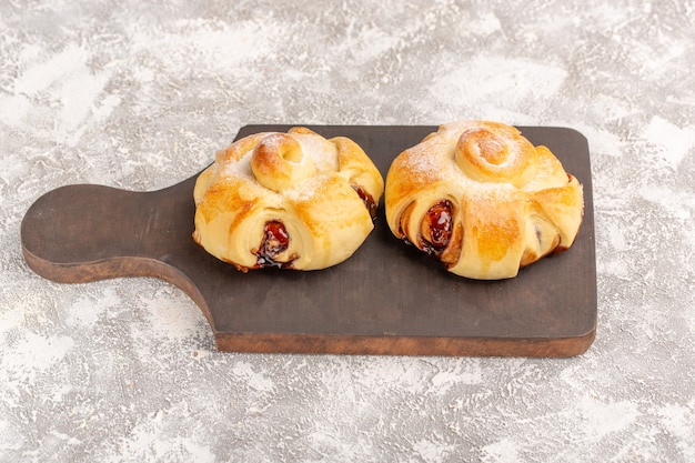 Foto gratuita vista frontale deliziosi pasticcini fruttati dolci al forno su scrivania grigia torta pasticceria dolce cuocere il tè