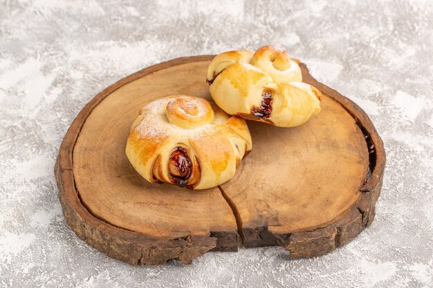 Front view delicious fruity pastries sweet baked on the grey-light wall cake pastry bake tea