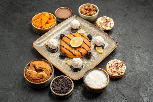 Front view delicious little cake with coconut candies on dark-grey background cake dessert biscuit pie cookie tea