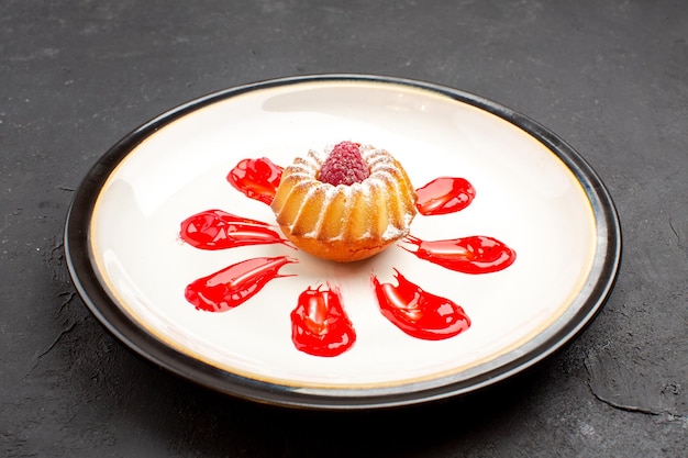 Front view delicious little cake with red icing inside plate on dark background tea sweet biscuit sugar pie cookie