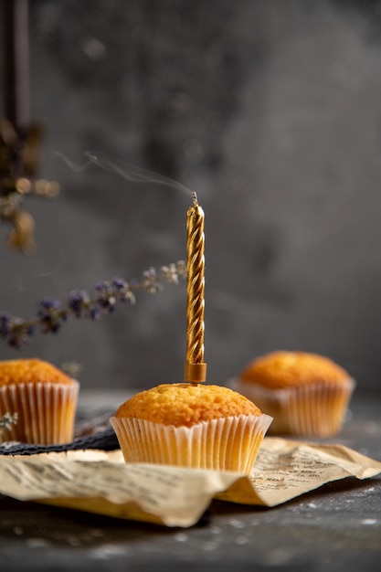 Una vista frontale deliziose torte con fiori viola sullo zucchero dolce del biscotto del tè del biscotto della tavola grigia