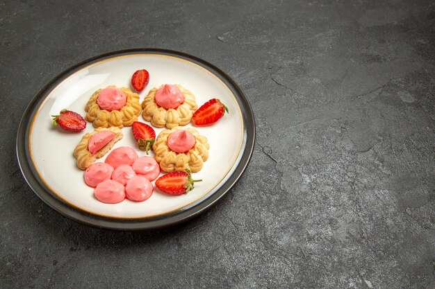 Front view delicious little cookies with pink cream inside plate on grey space