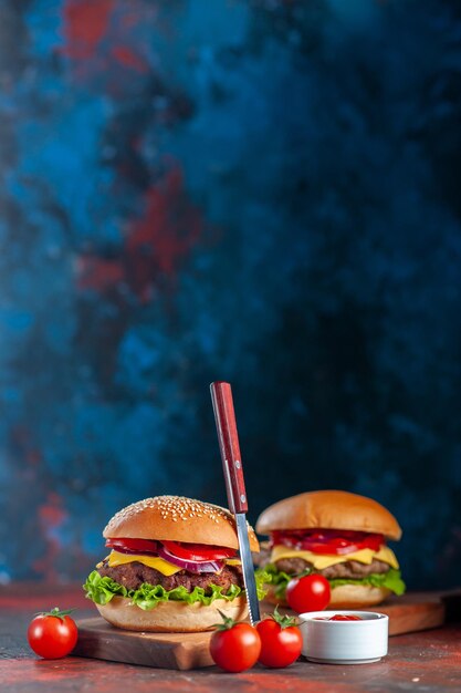 正面図まな板の上のおいしい肉チーズバーガー青い背景ファーストフードの食事スナックフライドポテトディナー料理サンドイッチ