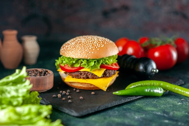 Foto gratuita vista frontale delizioso hamburger di carne con pomodori rossi su sfondo scuro