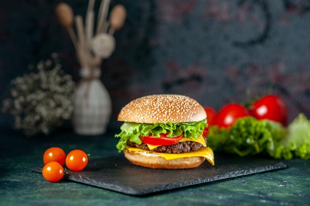 front view delicious meat hamburger with red tomatoes on dark background