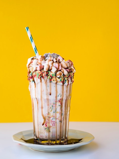 Front view of delicious milkshake with yellow background