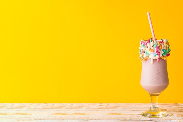 Front view of delicious milkshake in yellow background