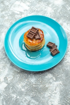 Muffin deliziosi vista frontale con miele e cioccolato sul tavolo luminoso