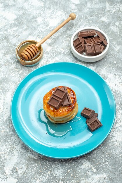 Front view delicious muffins with honey and chocolate on the light table