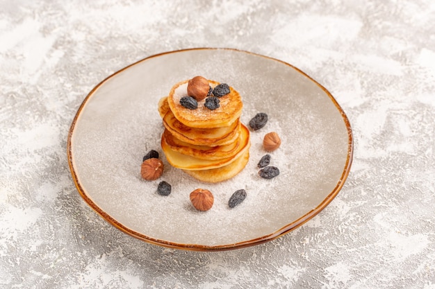 Front view delicious pancakes little with nuts inside plate on the grey-light surface pancake sweet food meal breakfast