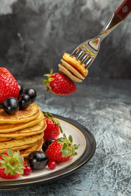 Front view delicious pancakes with fruits and berries on a dark surface dessert fruit cake