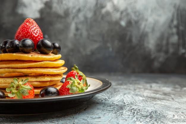 Free photo front view delicious pancakes with fruits and berries on a dark surface fruit cake dessert