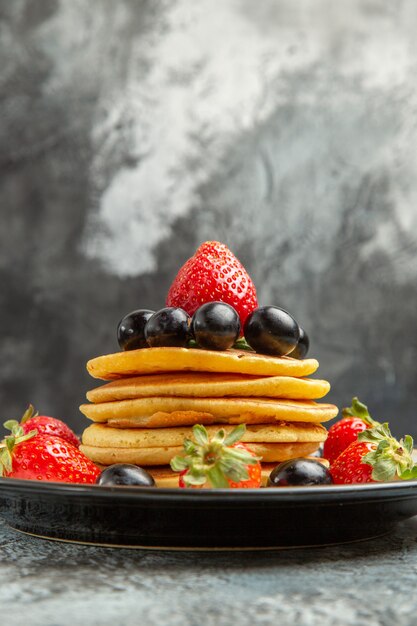 Front view delicious pancakes with fruits and berries on the dark surface fruit cake dessert
