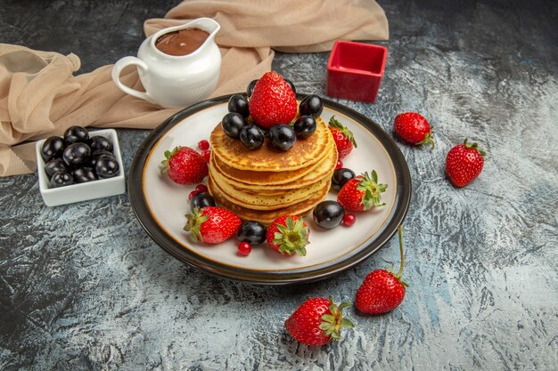 Front view delicious pancakes with fruits and berries on light surface fruit cake sweet