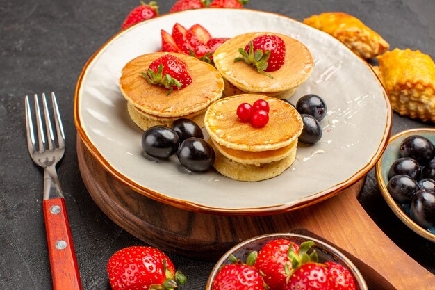 Free photo front view delicious pancakes with fruits on a dark surface cake fruit sweet pie