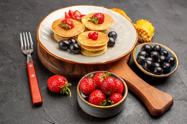 Foto gratuita vista frontale deliziose frittelle con frutta sulla superficie scura torta torta di frutta dolce