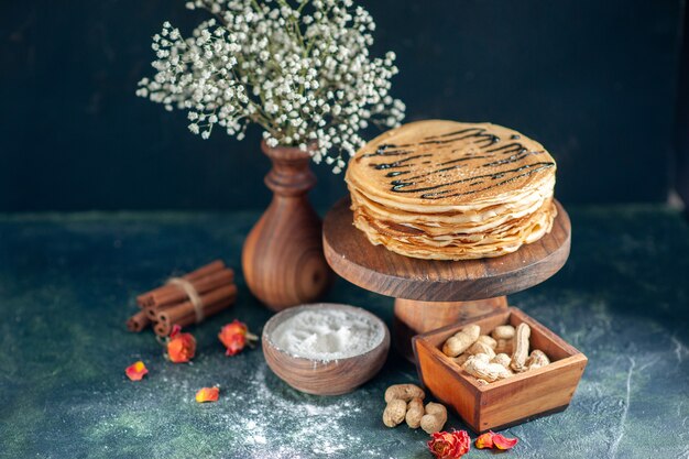 Вид спереди вкусные блины с орехами на темно-синем молочном десерте завтрак сладкий утренний пирог медовый пирог