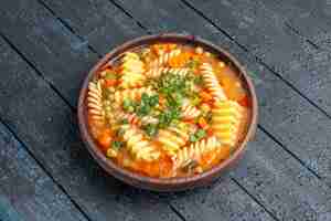 Foto gratuita vista frontale deliziosa zuppa di pasta di pasta italiana a spirale con verdure sul piatto da scrivania scuro zuppa di salsa di cena di pasta italiana