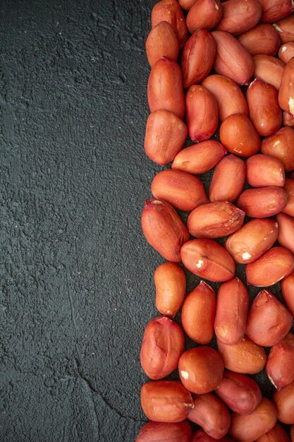 Front view of delicious peanuts arranged on the left side on black backgound with free space