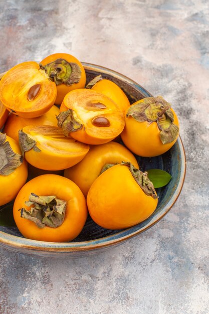Front view delicious persimmons in a bowl on nude