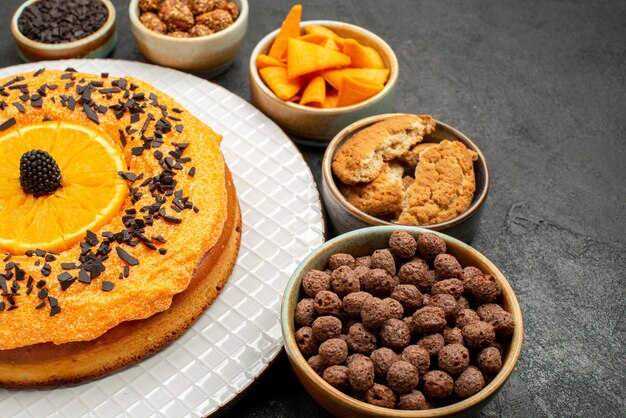 暗い背景のティービスケットフルーツデザートパイケーキにオレンジスライスと正面図おいしいパイ