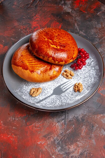 Front view delicious pies with red berries on a dark table sweet pastry pie cake