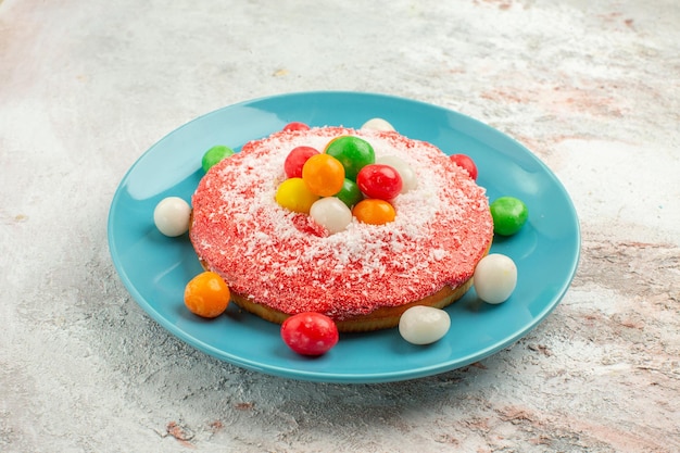 Front view delicious pink cake with colorful candies inside plate on white background pie rainbow color cake dessert candy