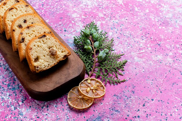 Вид спереди вкусный торт с изюмом, нарезанный пирог на розовой поверхности, выпечка, сахар, сладкое печенье, печенье