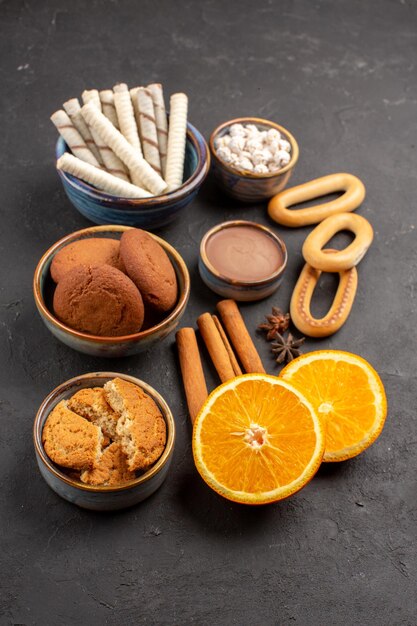 正面図暗い背景に新鮮なスライスしたオレンジとおいしい砂のクッキークッキー甘い柑橘類の砂糖ビスケットフルーツ
