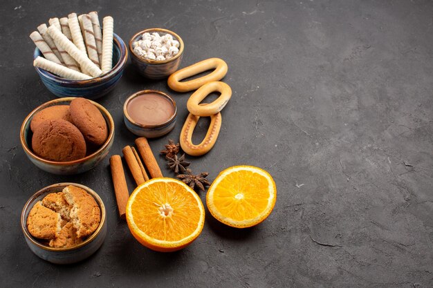 Front view delicious sand cookies with fresh sliced oranges on dark background cookie sweet citrus sugar biscuit fruit