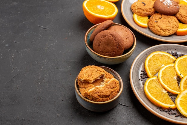Вид спереди вкусное песочное печенье со свежими нарезанными апельсинами на темном фоне сахарное печенье сладкое печенье фруктовый торт