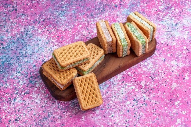 Вкусное печенье сэндвича вид спереди на розовом столе.