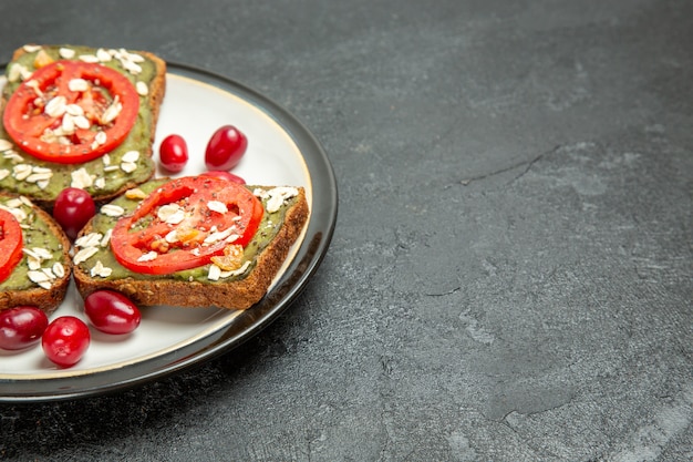 Вид спереди вкусные бутерброды с пастой из авокадо и помидорами внутри тарелки на сером фоне булочка с гамбургером закуска хлеб