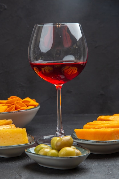 Front view of delicious snacks for wine in a glass goblet on a black background