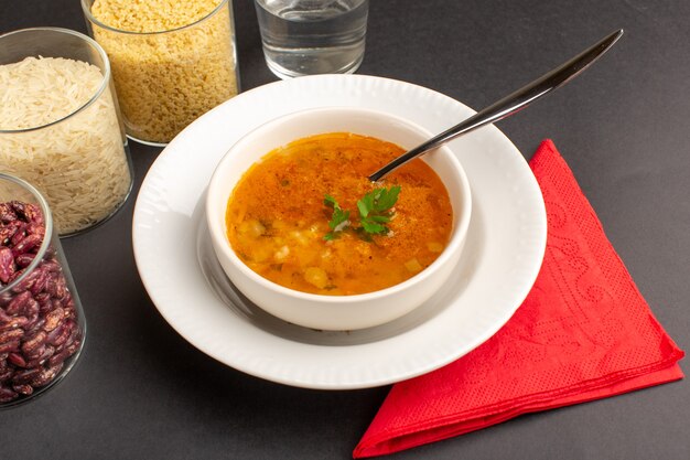 Front view of delicious soup inside plate with beans on dark desk