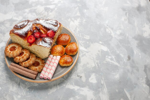 Front view delicious strawberry cake with cookies and little cakes on the white surface