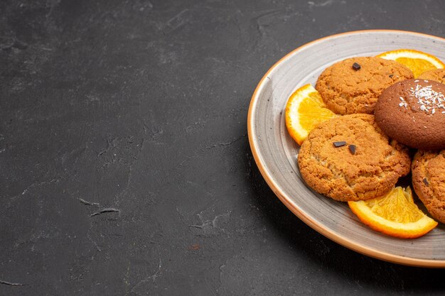 Вид спереди вкусное сахарное печенье с нарезанными апельсинами внутри тарелки на темном фоне сахарное печенье сладкое печенье фрукты