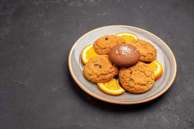 Вид спереди вкусное сахарное печенье с нарезанными апельсинами внутри тарелки на темном столе, сахарное печенье, сладкое печенье