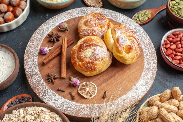 Вид спереди вкусные сладкие булочки с орехами на сером цвете торта сахарное тесто пирог горячее запекать чай