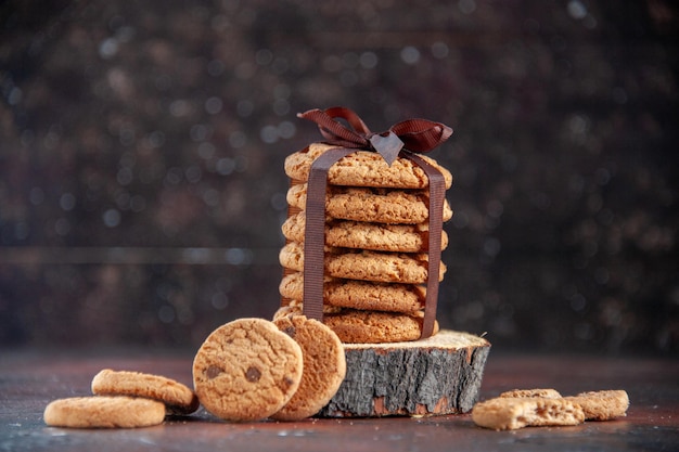 Foto gratuita biscotti dolci deliziosi di vista frontale legati con l'arco sul biscotto dolce del tè dello zucchero del dessert del fondo scuro