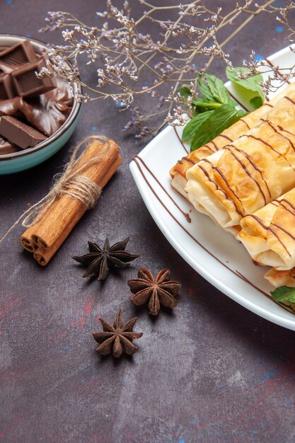 Вид спереди вкусной сладкой выпечки с шоколадом на темном пространстве