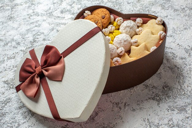 Вид спереди вкусные сладости, печенье, печенье и конфеты внутри коробки в форме сердца