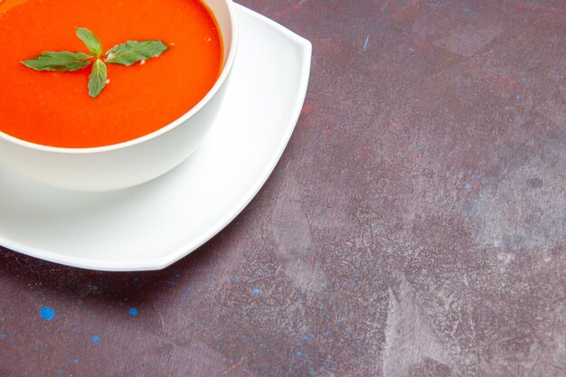暗いスペースに皿の中に一枚葉が入った正面のおいしいトマトスープのおいしい料理