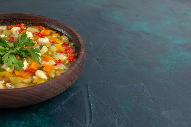 Front view delicious vegetable soup with different ingredients inside brown plate on the dark desk