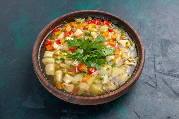 Front view delicious vegetable soup with different ingredients inside brown pot on dark desk